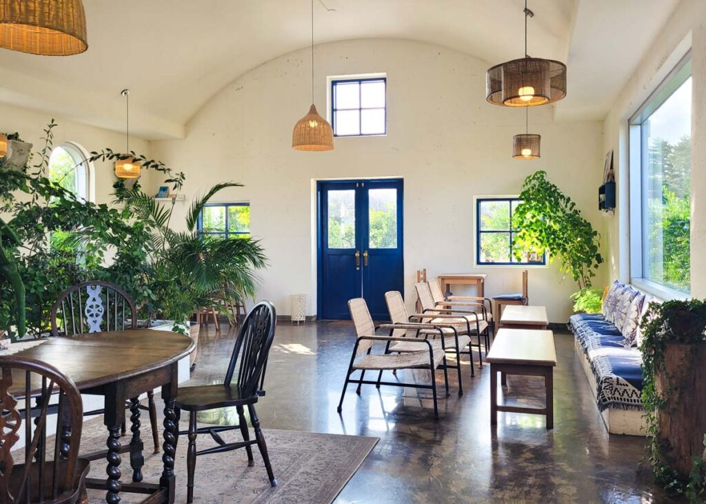 interior of cafe dendri with cushion benches, chairs and woven hanging lamps inside greek style cafe